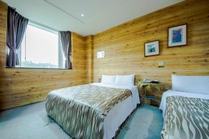 two beds in a room with wooden walls at Songyuan B&B in Lugu Lake