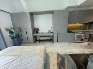 ドバイにあるBrand New Chic Studio Apartment 8min to Downtownのベッドとテーブルとキッチンのある寝室