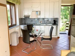 a kitchen with a glass table and black chairs at Parco Ameno by Lago Reisen in Germignaga +4 photos