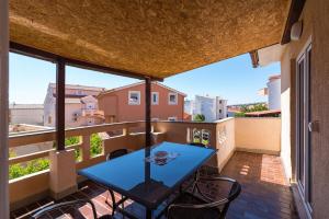 - Balcón con mesa azul y sillas en Ivy Apartments in Center, en Novalja