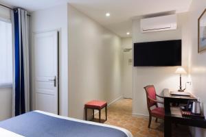 a hotel room with a bed and a desk and a television at Hotel Mogador in Paris
