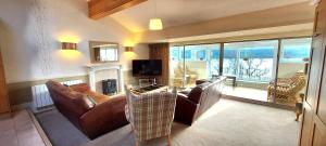 a living room with a couch and a tv and a fireplace at Loch Rannoch Highland Club in Kinloch Rannoch