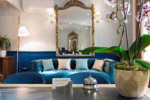 - un canapé bleu dans le salon avec un miroir dans l'établissement Hotel Mogador, à Paris