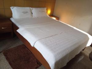 a large bed with white sheets and pillows at Patty Lodge in Muleba