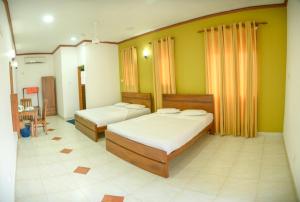 two beds in a room with yellow walls at Lake House Rest - Kataragama in Kataragama