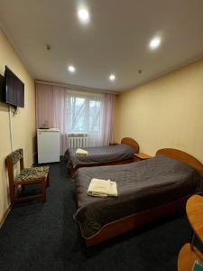 a hotel room with three beds and a chair at Готельно-ресторанний комплекс Поділля in Bershadʼ