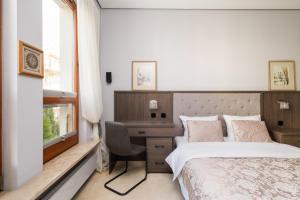 a bedroom with a bed and a desk and a window at Royal Wilanów Spacious Apartment by BookingHost in Warsaw