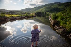 Ein kleines Mädchen stand im Wasser in der Nähe eines Flusses in der Unterkunft Arctic photo retreat Lofoten - lakehouse Bjørkly in Vestvågøya