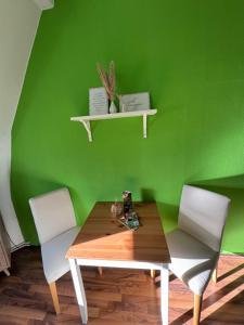a green wall with a wooden table and two chairs at Villa Meuselwitz in Meuselwitz