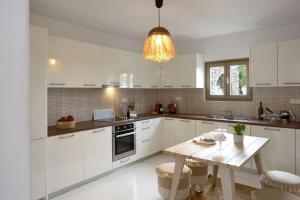 eine Küche mit weißen Schränken und einem Holztisch in der Unterkunft Executive Paros Villa 4 Bedrooms Villa Almyrikia Sunset Stunning Sea View in Kampos Paros