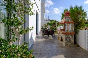 a small patio with a table and a stone fireplace at Eden Blue Villa by Nomads in Emba