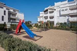 ein Spielplatz mit Rutsche vor einem Gebäude in der Unterkunft Isla Candor free parking by Staycare in Rota