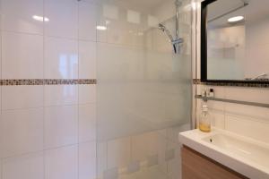 a white bathroom with a shower and a sink at Hotel Geoffroy Marie Opéra in Paris +13 photos