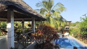 a villa with a swimming pool and a thatch roof at AKINE TI KASSO piscine in Diembéreng