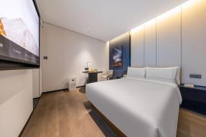 a bedroom with a large white bed and a table at Atour Hotel Beijing Zhongguancun Renmin University in Beijing