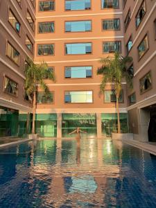 a man standing in a pool in front of a building at โรงแรม อีส จอมเทียน บี in Jomtien Beach