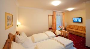 Habitación de hotel con 2 camas y sofá en Hotel Hammerwirt - Forellenhof, en Untertauern