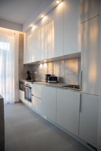 a large kitchen with white cabinets and appliances at Elegant Villa Cataleya with private pool and sauna in Novalja