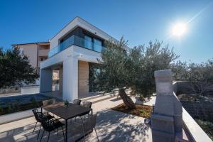 a house with a table and chairs in front of it at Elegant Villa Cataleya with private pool and sauna in Novalja