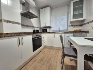 a kitchen with white cabinets and a table with a chair at C01A07 Moderno apartamento con vistas in Santander