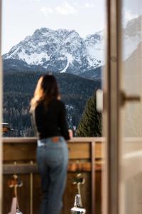 a woman looking out a window at a snow covered mountain at le Gemme - Dolomites escape in Dosoledo