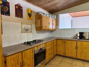 a kitchen with wooden cabinets and a stove top oven at CMK Lodge in Hartbeespoort