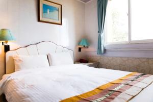 a bedroom with a white bed and a window at Dajenshan Hotel in Kenting