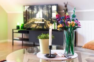 una sala de estar con una mesa con una vela y flores en Waldbewohner Apartments / Hirsch, en Ilsenburg