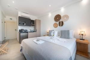 a bedroom with a large white bed and a kitchen at Ocean View Studios and Luxury Rooms in Plomari