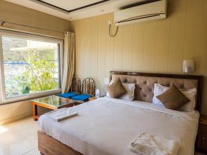 Un dormitorio con una cama grande y una ventana en Karwaan by the Ganges, en Rishīkesh