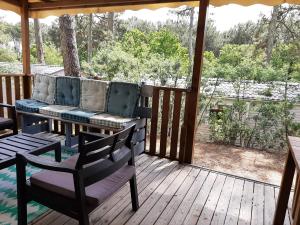 un porche cubierto con sofá y sillas en Mobilhome Mobil home Cap ferret, en Claouey