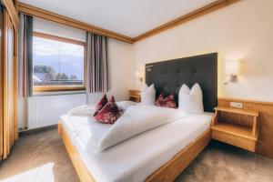 Un dormitorio con una gran cama blanca con almohadas rojas. en Apart Breila, en Serfaus