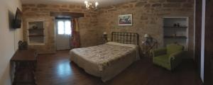 a bedroom with a bed and a green chair at La Posada de Pedrazales in Pedrazales