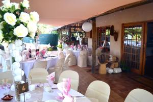 a room with white tables and white chairs and flowers at Midrand Wild Goose Guest House B&B in Midrand +97 photos