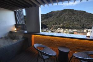 a balcony with two chairs and a view of a mountain at Aura Tachibana in Hakone
