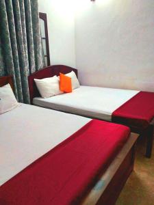 two beds in a room with red and white at Salmanel Resort Ayagama - Rathnapura in Ratnapura