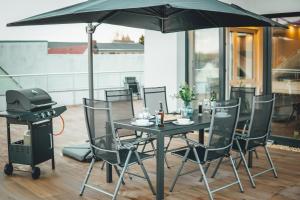 a table and chairs with an umbrella and a grill at ProZone Gaming Apartment in Hainichen