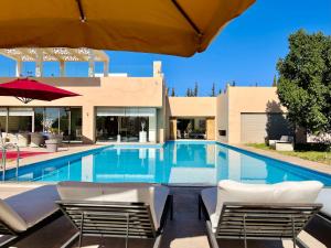 a swimming pool with white chairs and a building at Hala Luxury Domain in Marrakesh
