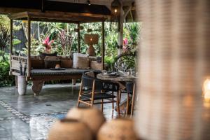 a patio with a couch and a table and chairs at Rimba by Hari Indah in Uluwatu
