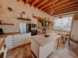 a kitchen with white cabinets and a table with chairs at La Maison Des Pierres Blondes in Orban