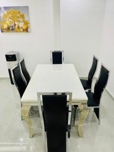 einen weißen Tisch mit vier schwarzen Stühlen und einem Gemälde in der Unterkunft Aqua Luxury homes in Mombasa + 25 Fotos