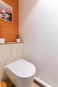a bathroom with a white toilet and an orange wall at Le Duplex des Docks by So Homy - 2 Bed Room - 4 PAX in Saint-Ouen +45 photos