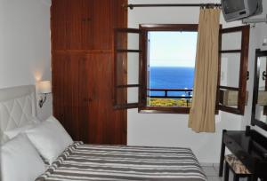 a bedroom with a window with a view of the ocean at Pennystella Apartments in Agia Pelagia