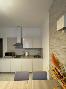 a kitchen with white cabinets and a table and chairs at Taikos Apartmentai 2 in Druskininkai