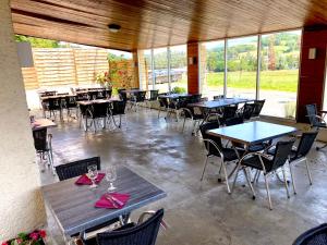 an empty restaurant with tables and chairs and windows at Auberge de la Source in Chazey-Bons