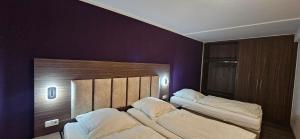 two beds in a room with purple walls at Apartment Hotel Citylight in Cologne