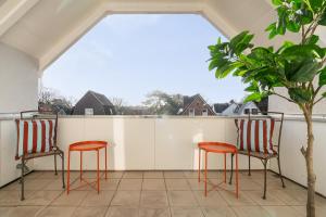 two chairs and a table on a balcony at CLS Moderne Villa Bad Schwartau mit Garten für bis zu 6 Personen, 2 E-Ladesäulen, 3 Parkplätze, Loggia, Big GREEN EGG, Massagesessel, großes Haus zwischen Lübeck und Ostsee, ideale A1 Anbindung nach Hamburg, Lübeck, Timmendorfer Strand in Bad Schwartau