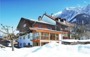a house in the snow with mountains in the background at Helle Ferienwohnung In Ehrwald in Ehrwald