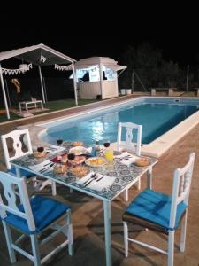 einen Tisch mit Essen neben einem Pool in der Unterkunft Casa Rural El Almendro in Olvera