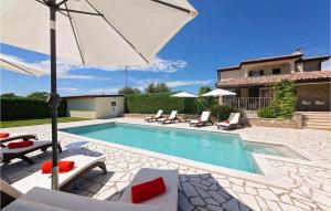 a swimming pool with chairs and an umbrella next to a house at Villa Inga in Buje